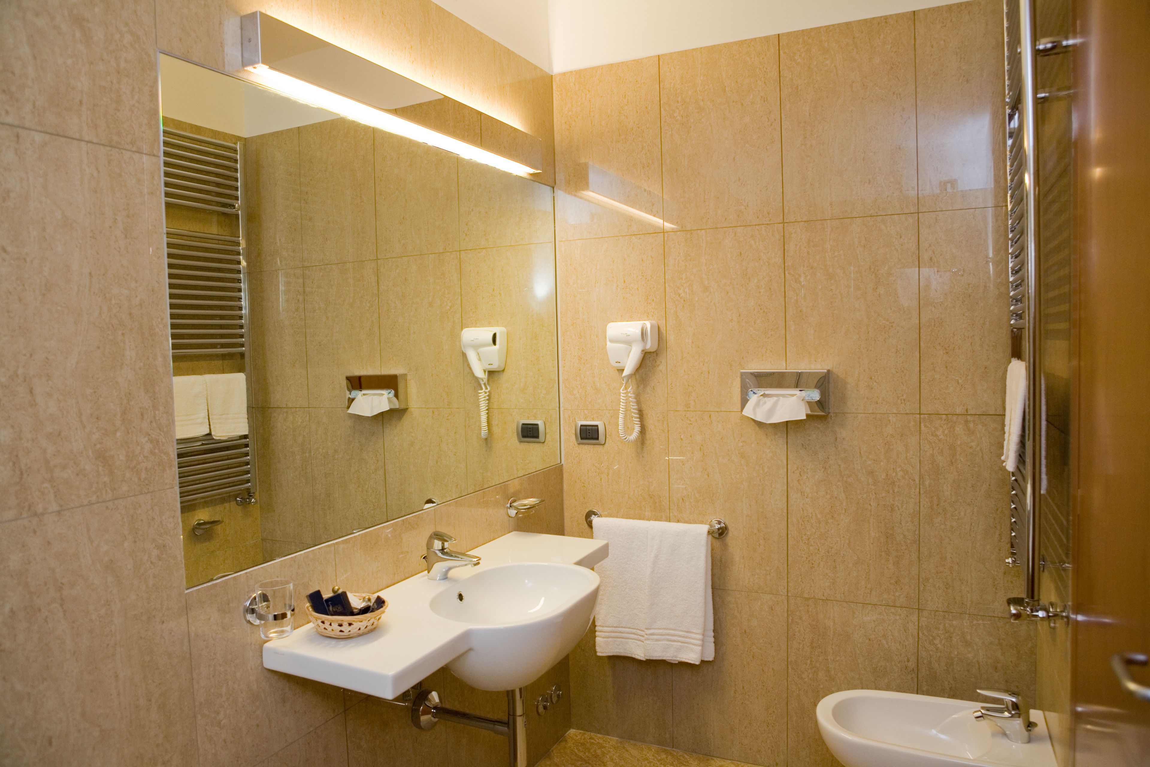 A modern bathroom with a large mirror, two sinks, and a glass shower enclosure.