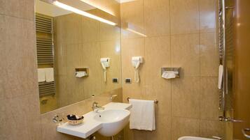A modern bathroom with a large mirror, two sinks, and a glass shower enclosure.