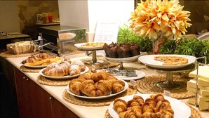 A buffet with various pastries and a floral centerpiece. - Hotel Airone (Grosseto)