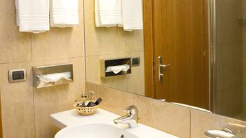 A bathroom with a sink, mirror, towel rack, and a shower area.