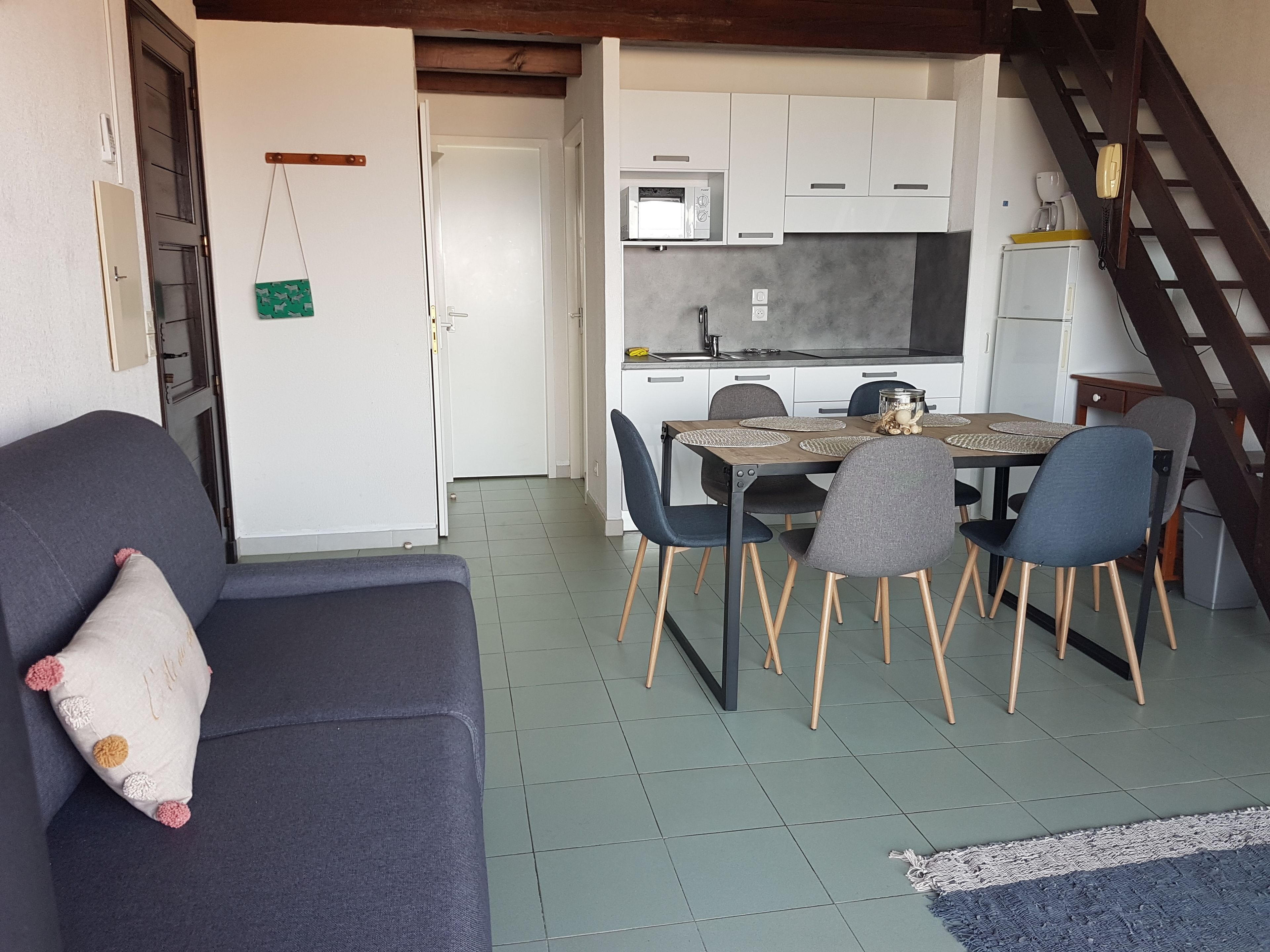 Um espaço compacto com sofá, mesa de jantar, cadeiras e cozinha compacta.