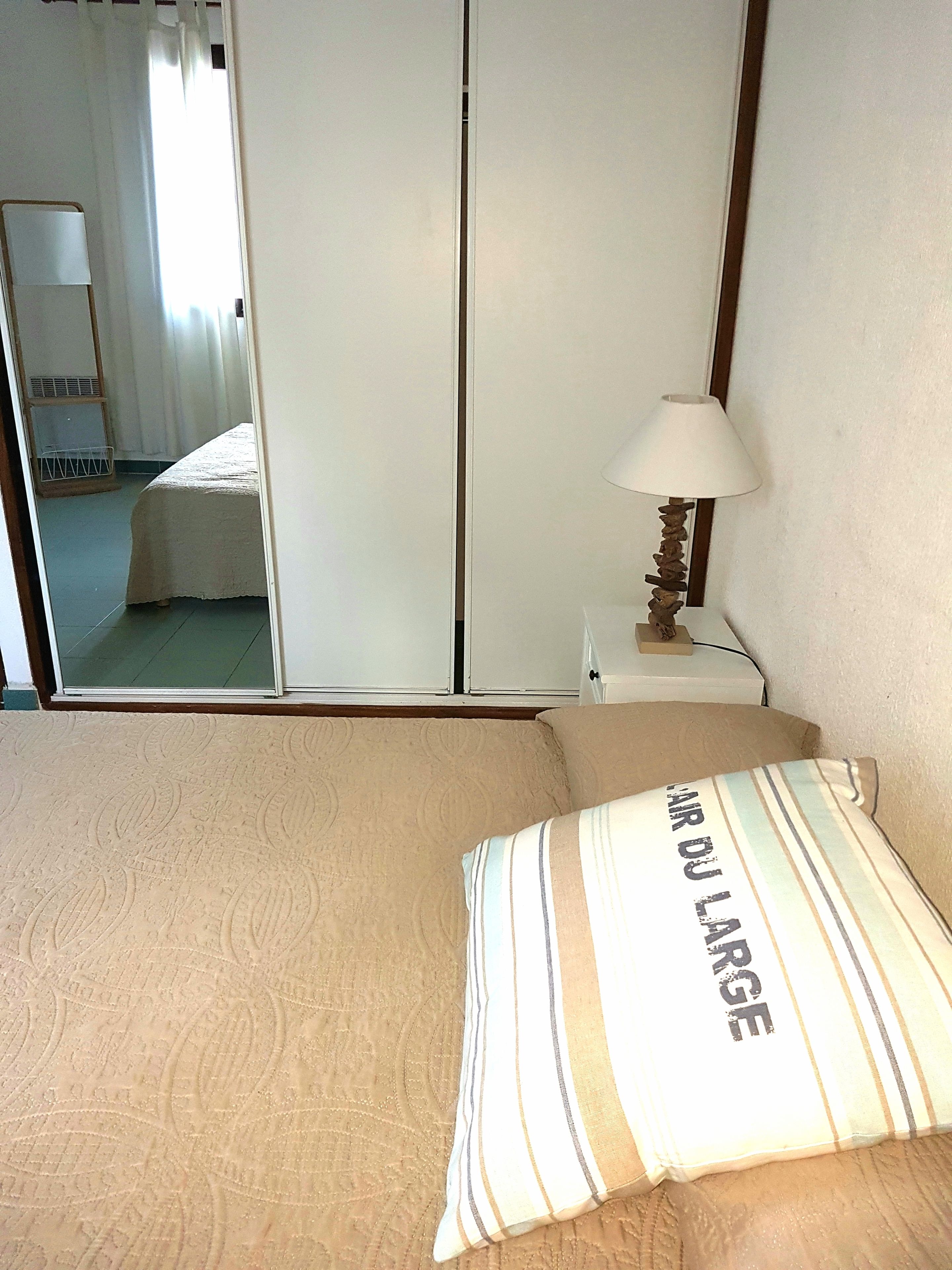 A bedroom with a bed, a bedside lamp, and a mirror.