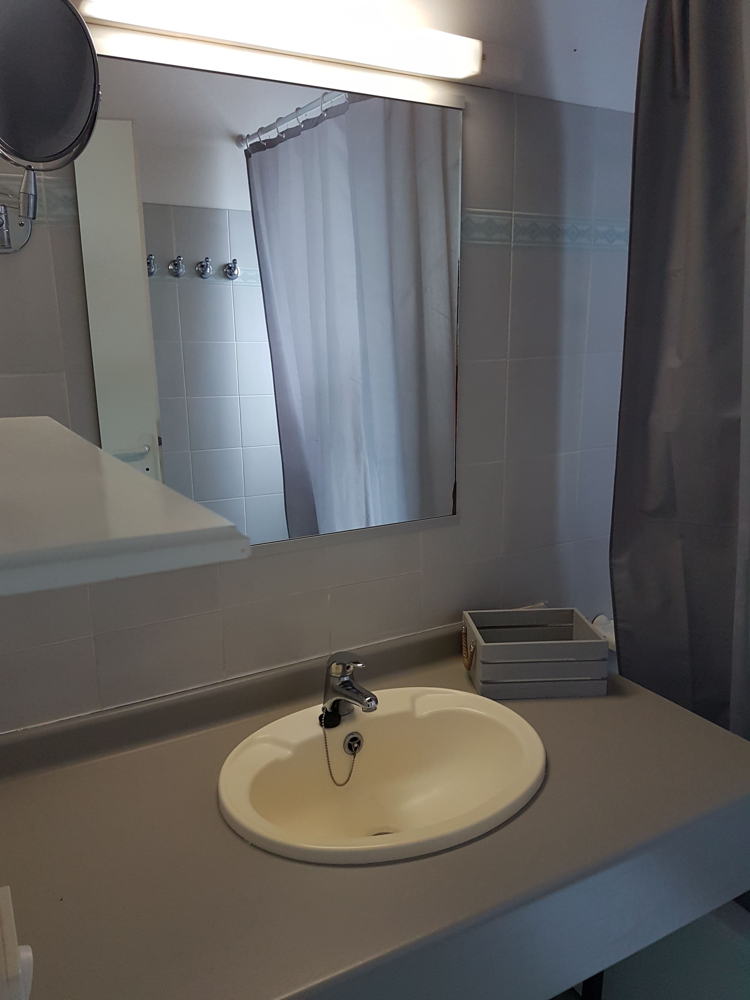 A bathroom with a white sink, a mirror, and a shower curtain.