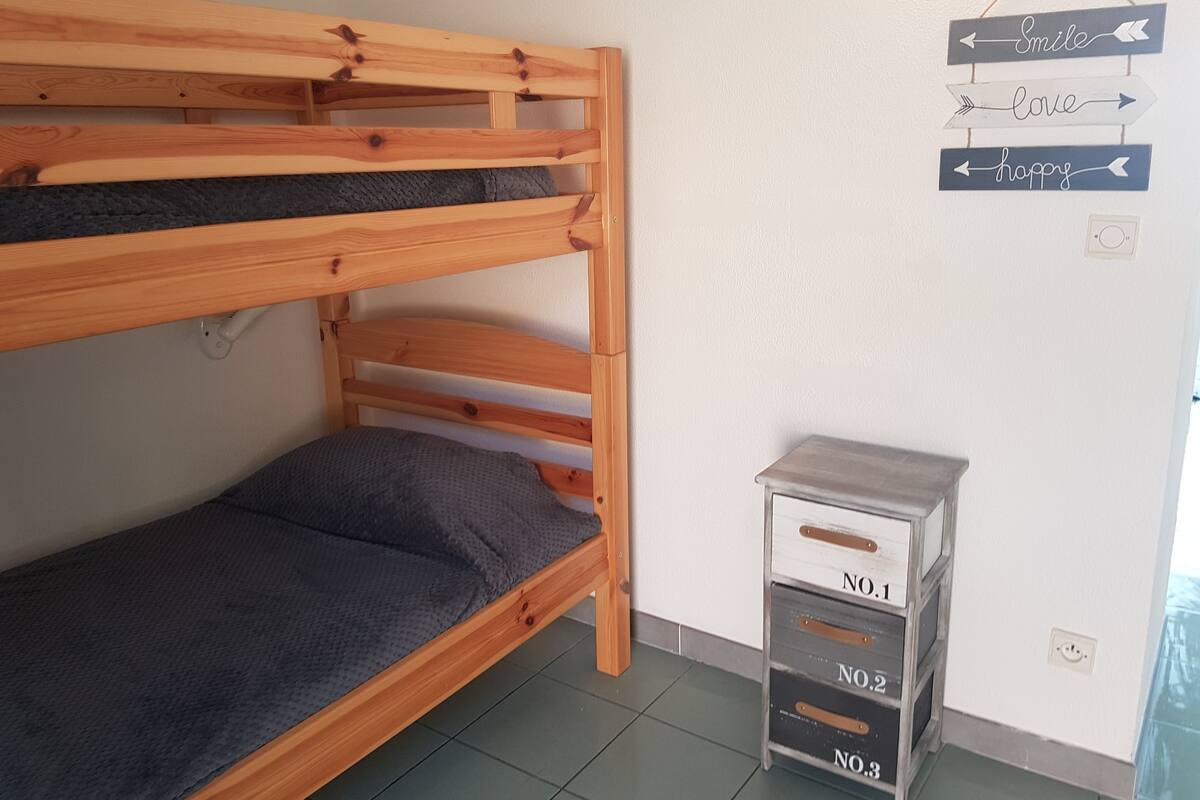 A bunk bed with a gray mattress and a small metal storage unit with drawers labeled NO.1, NO.2, and NO.3.
