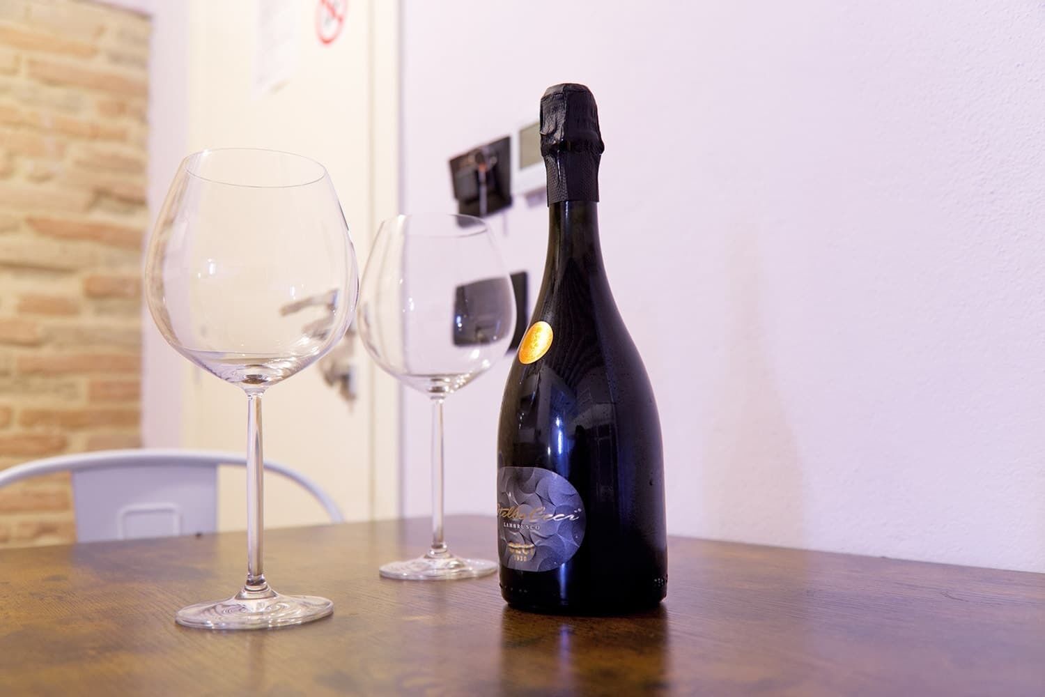 Una botella de champán y dos copas de vino vacías sobre una mesa de madera.