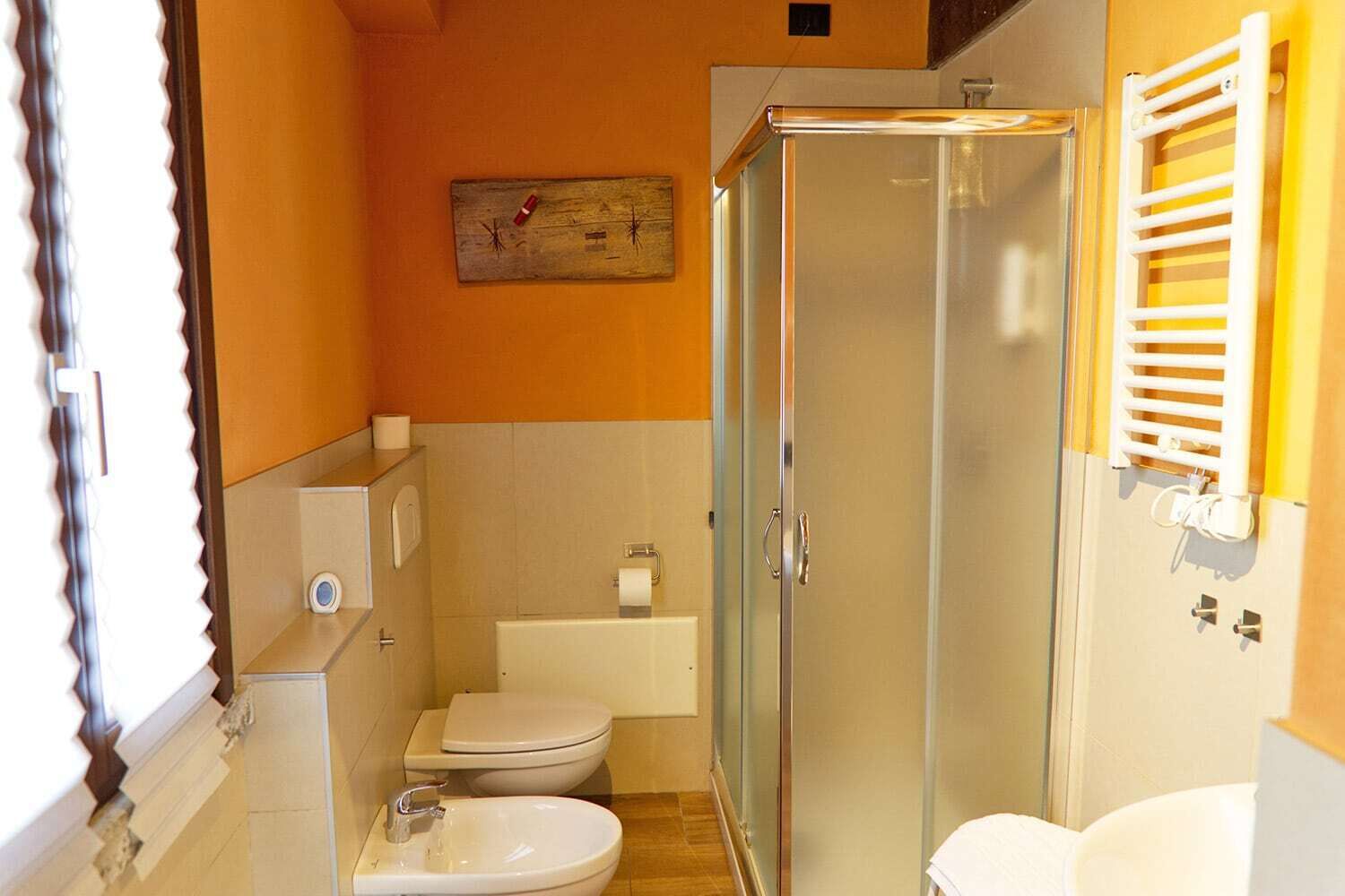 Casa de banho com chuveiro em cabine de vidro, sanita e lavatório.