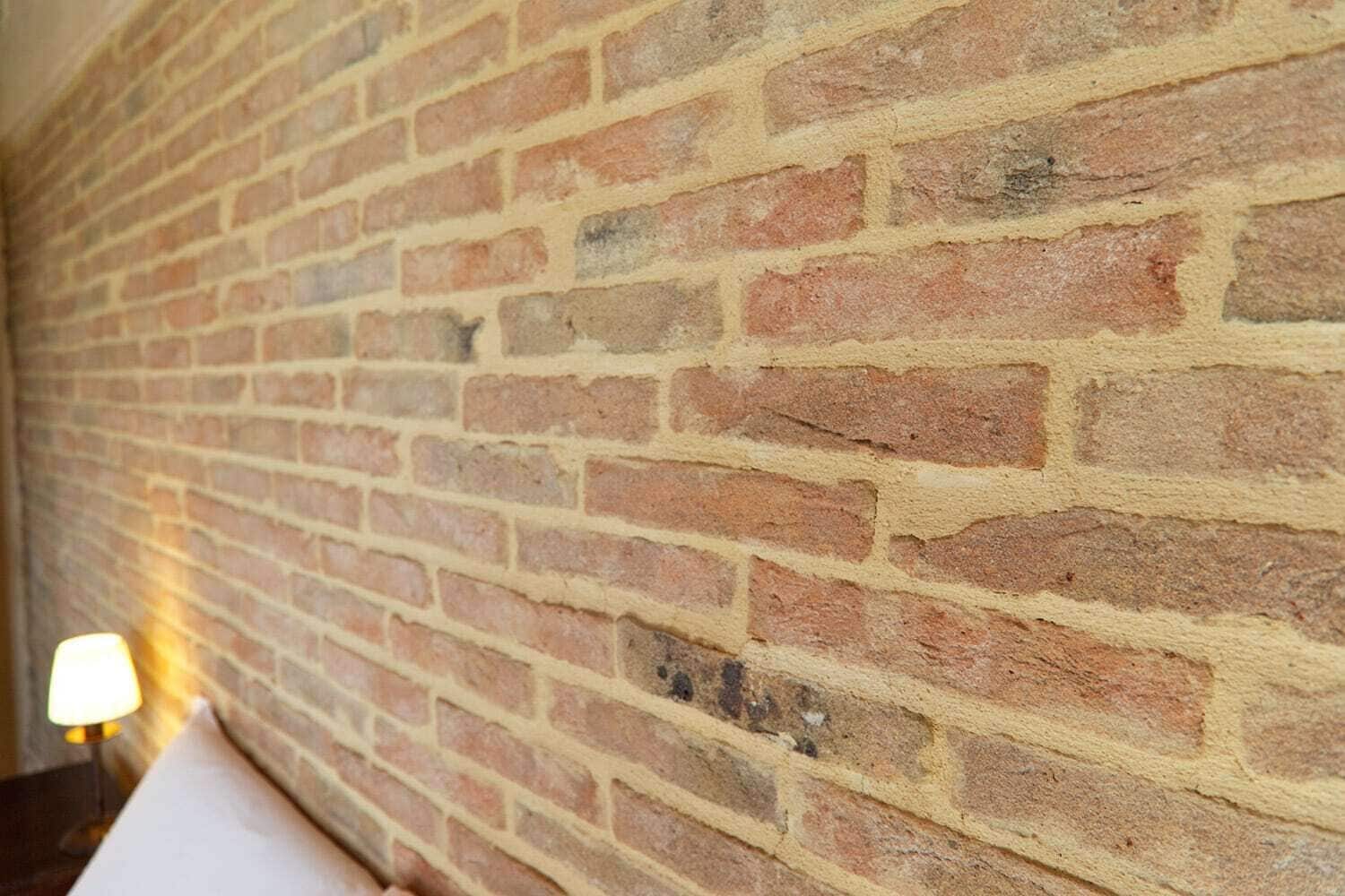 A brick wall with a consistent pattern and a lamp on the left side.
