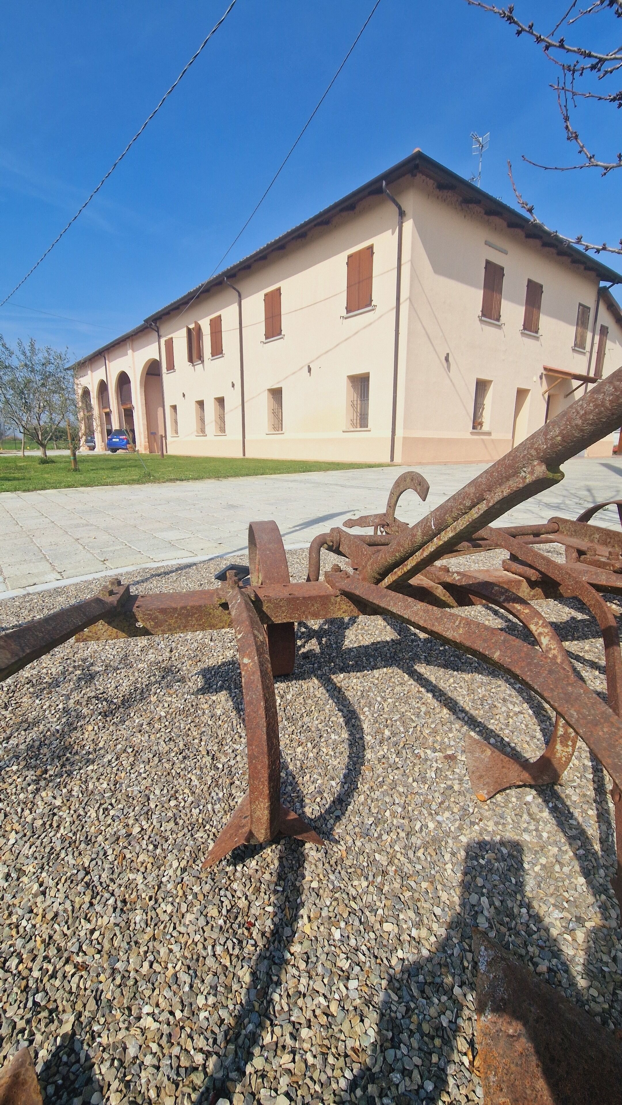 Un bâtiment à la façade beige, doté de nombreuses fenêtres et dont le sol est recouvert de gravier.