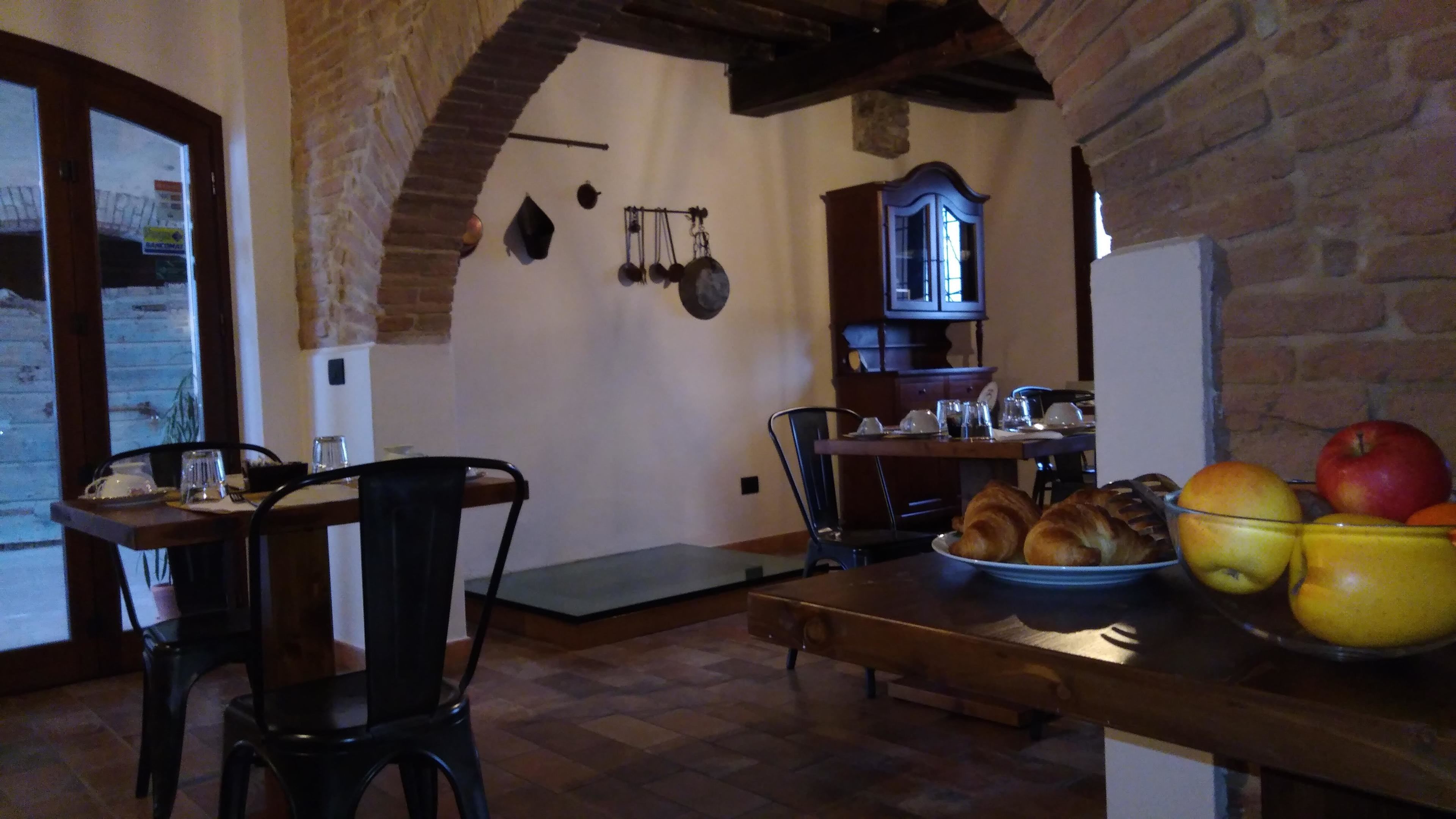 A rustic kitchen with exposed brick walls, wooden beams, and a dining area with a table set for two.