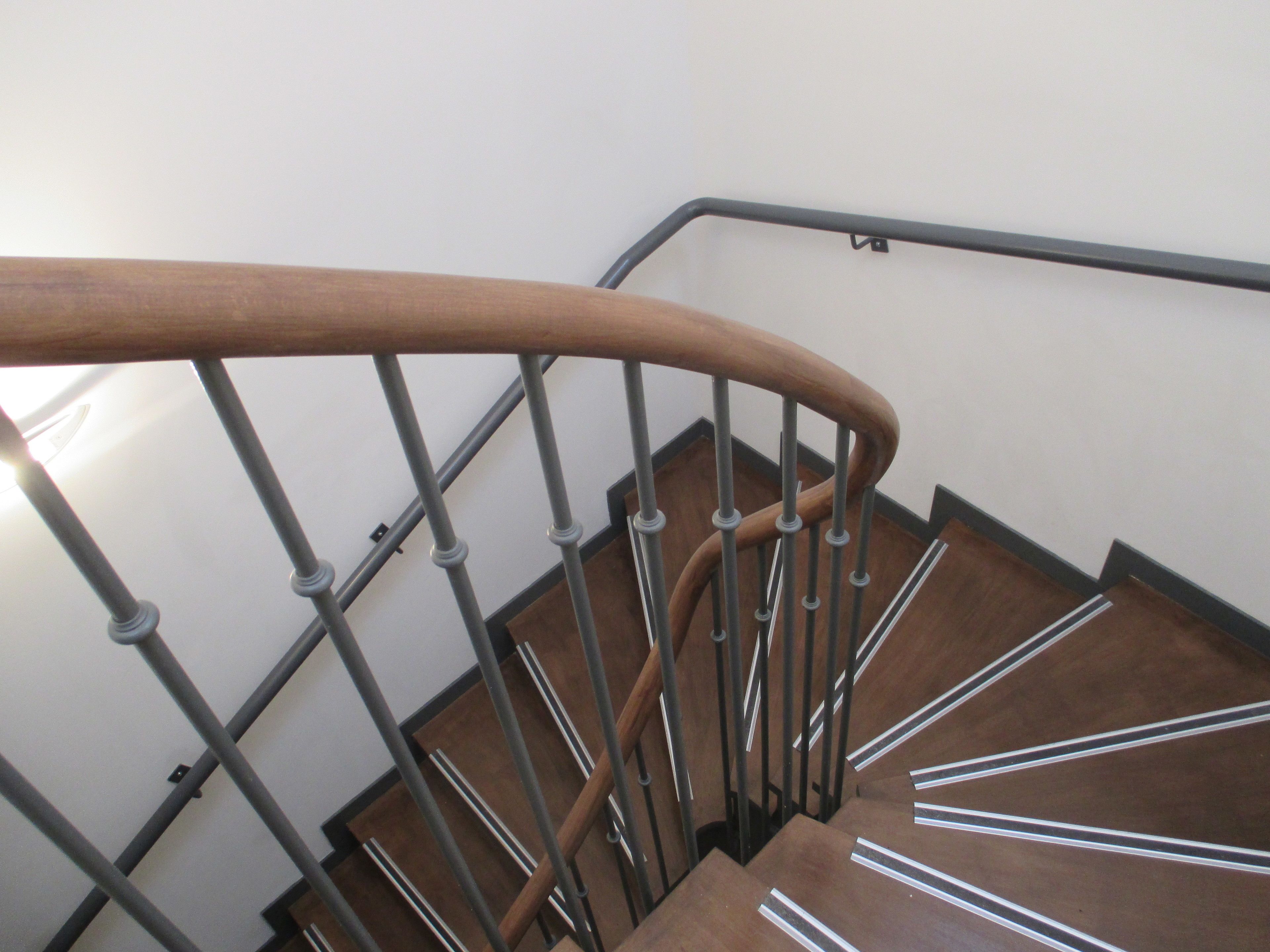 Barandilla de madera con balaustrada de metal en una escalera.