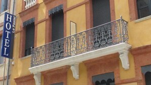 Un hotel con balcón y barandilla de hierro forjado decorativa.