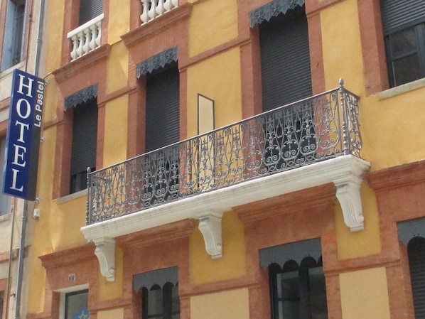 Un hotel con balcón y barandilla de hierro forjado decorativa.