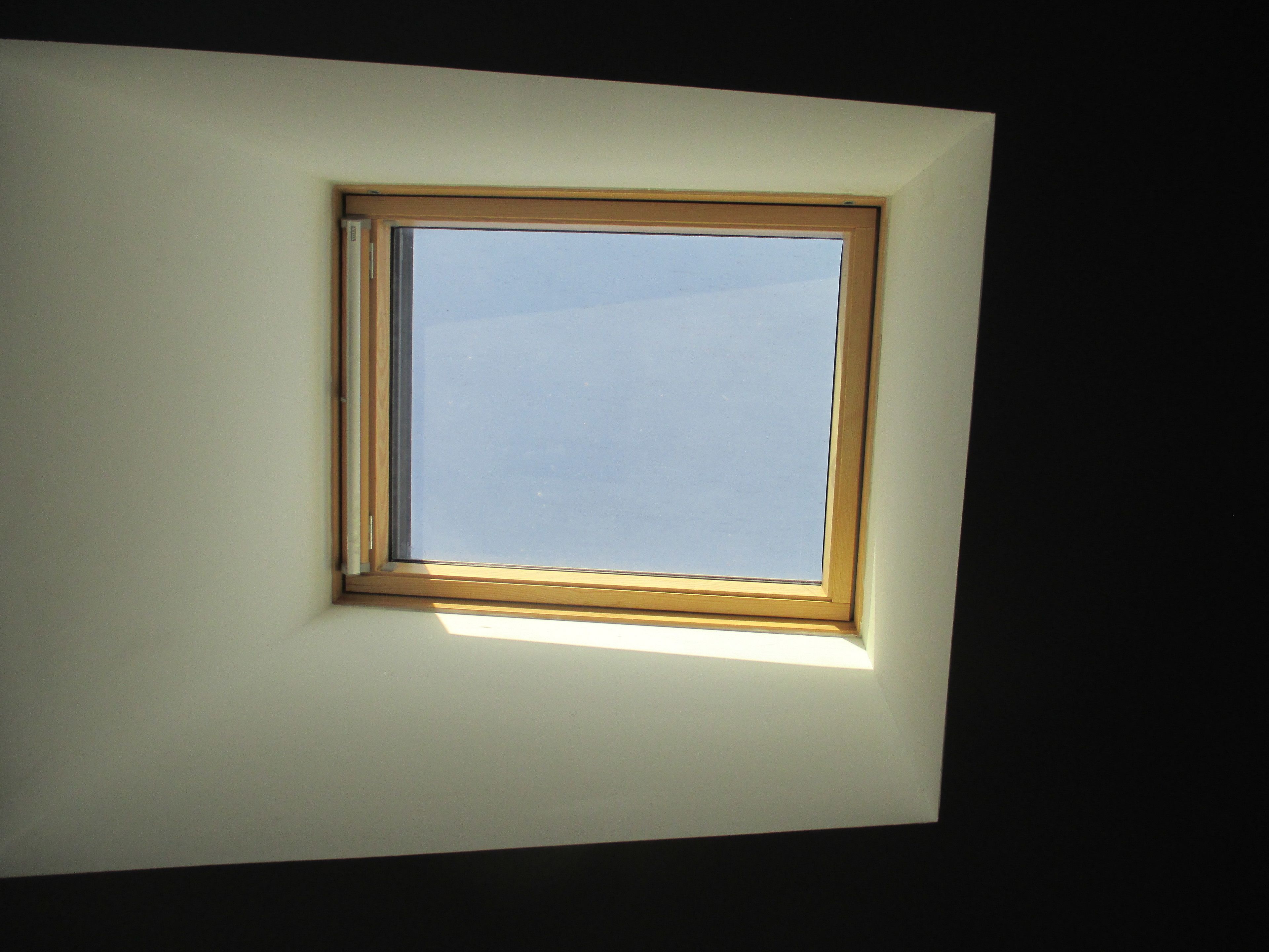 A skylight window in a room with white walls.