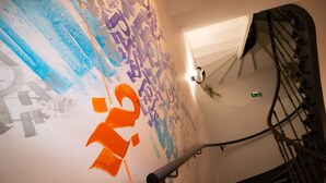Una escalera con barandilla, una pared con grafitis y una lámpara.