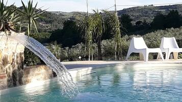 Piscina a l'aire lliure, piscina amb cascada, para-sols i gandules