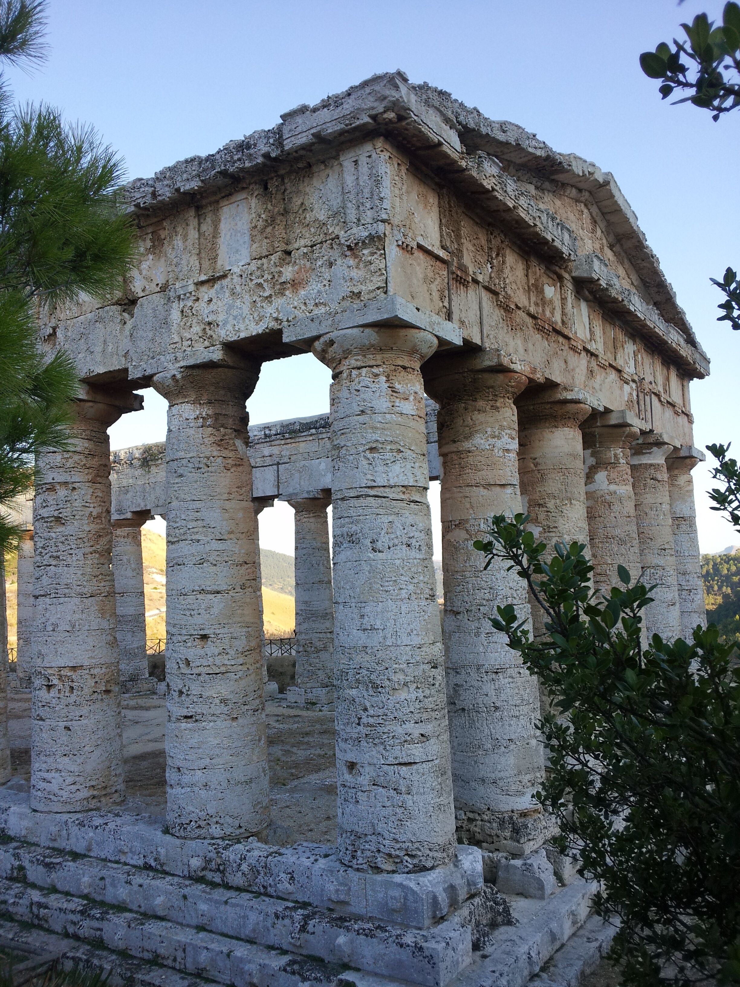 De vieilles colonnes de pierre, surmontées d’un toit plat, et entourées de verdure.