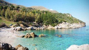 A coastal landscape with clear turquoise waters, rocky shore, and a hillside with dense greenery. - La Suite di Segesta (Calatafimi)
