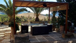 An outdoor patio with stone flooring, wicker furniture, and potted plants. - La Suite di Segesta (Calatafimi)