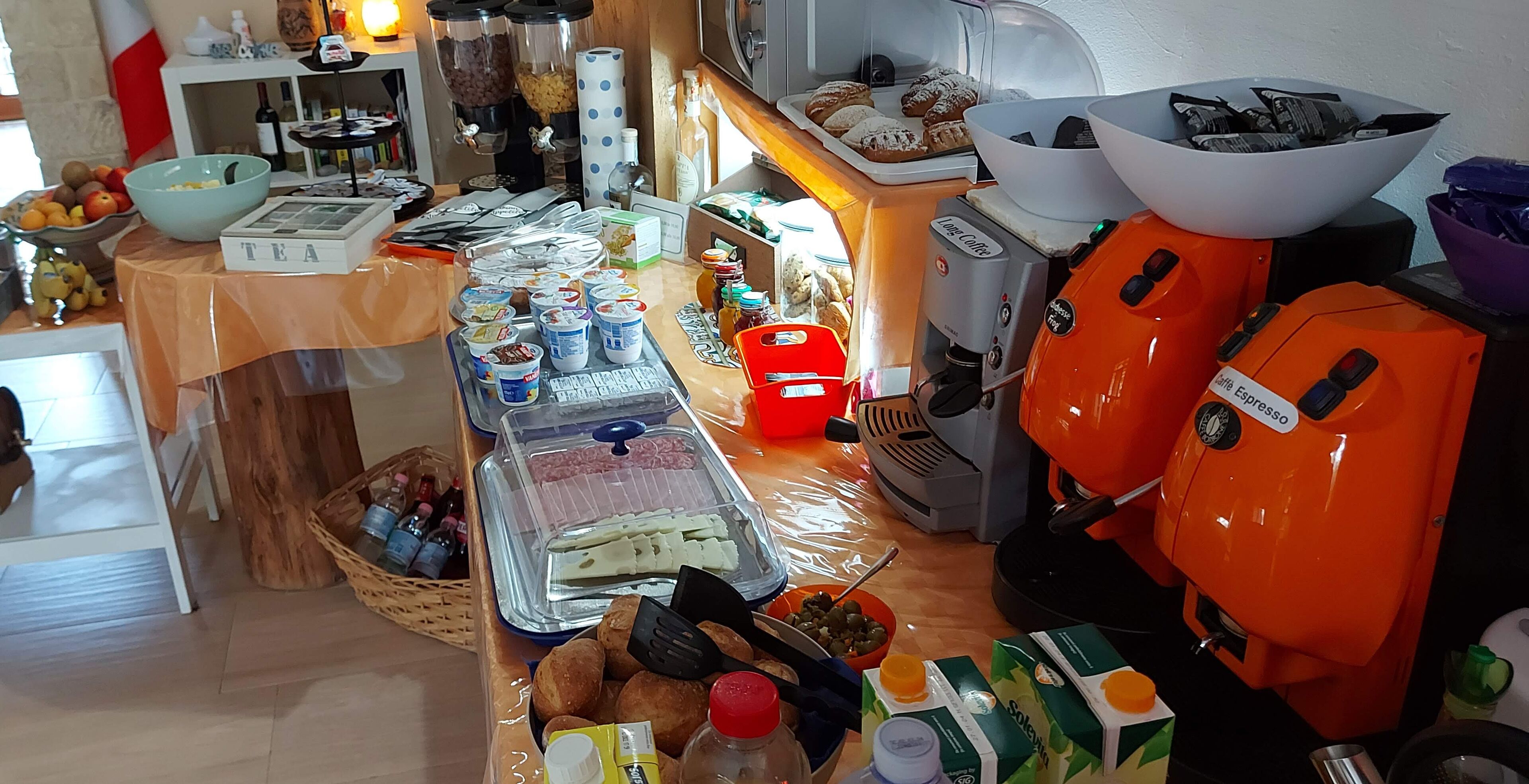 Una zona de cocina con cafetera, estación de té y diferentes alimentos.