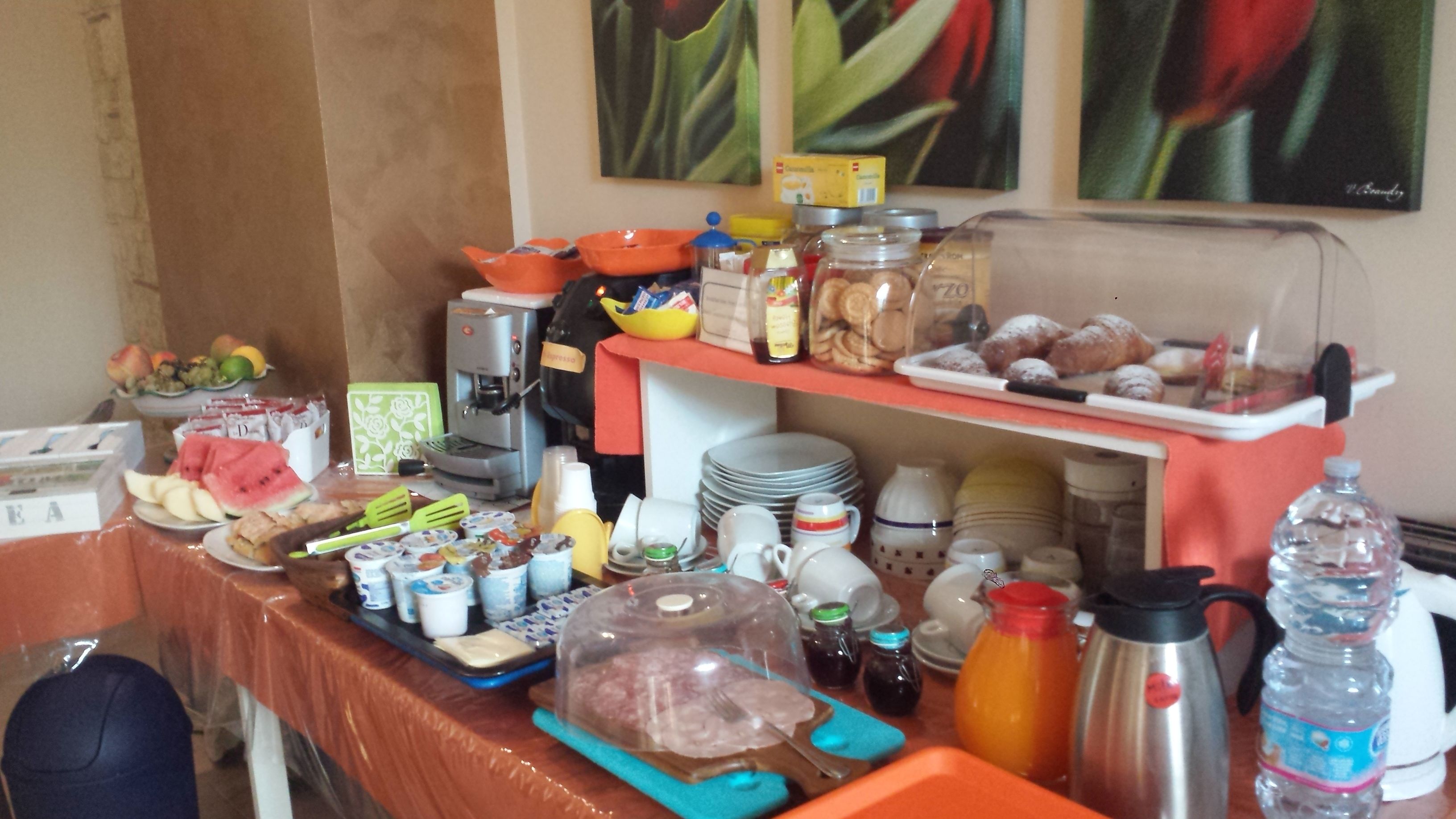 A buffet setup with various food items, a coffee machine, and condiments.