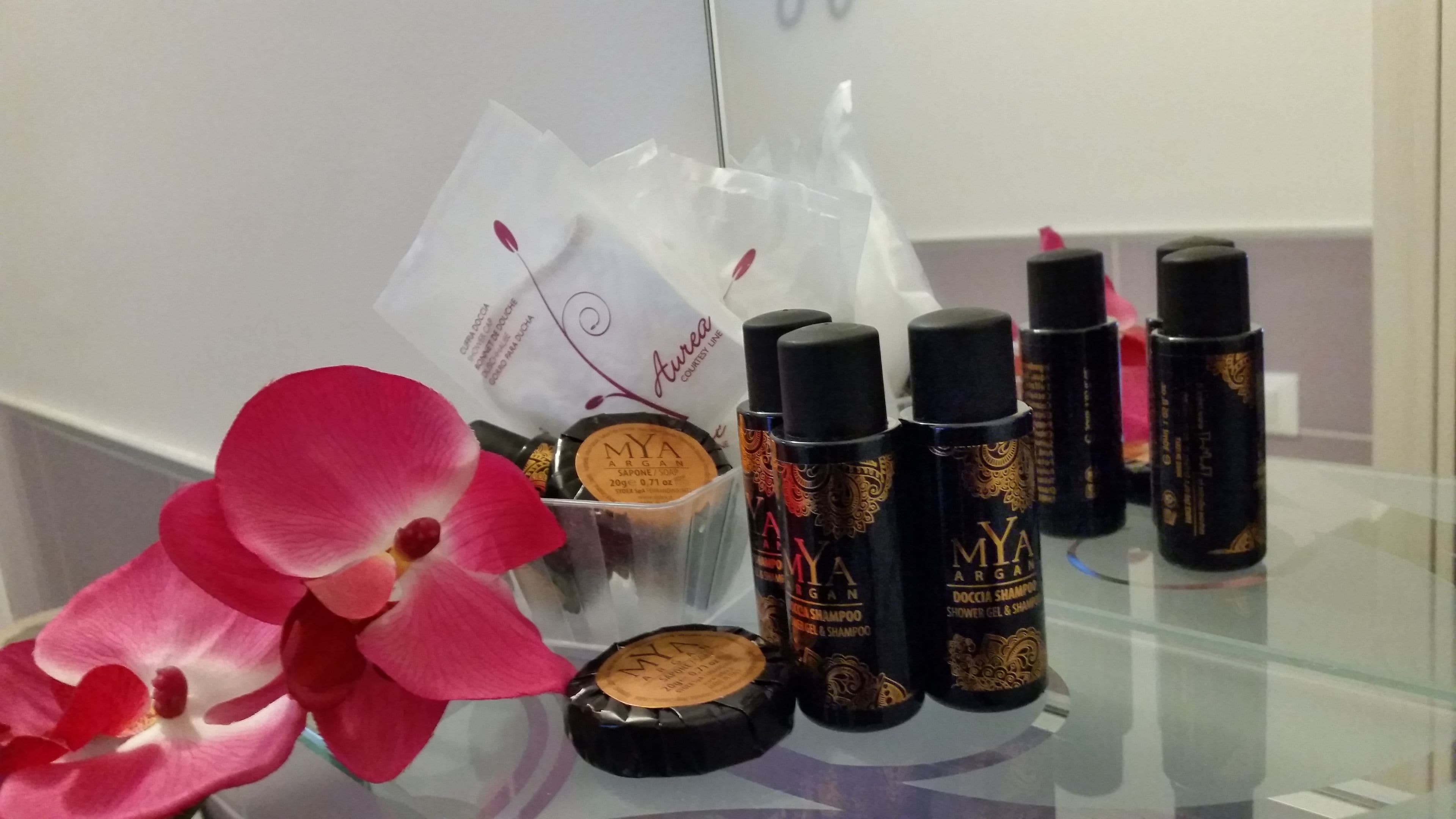 Una exhibición de productos cosméticos sobre una mesa de vidrio, incluyendo botellas de champú y un polvo compacto.