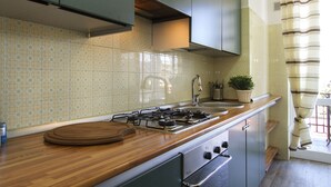 Cozinha com fogão a gás, bancada de madeira e eletrodomésticos de aço inoxidável.