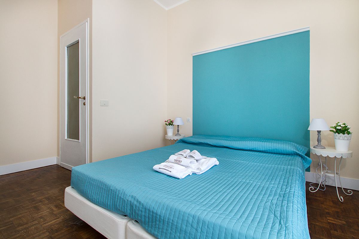 A bedroom with a large bed, a teal headboard, and a white door.