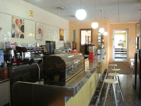 A cafe with a counter, coffee machines, and stools. - Hostal Millan (Sot de Ferrer)