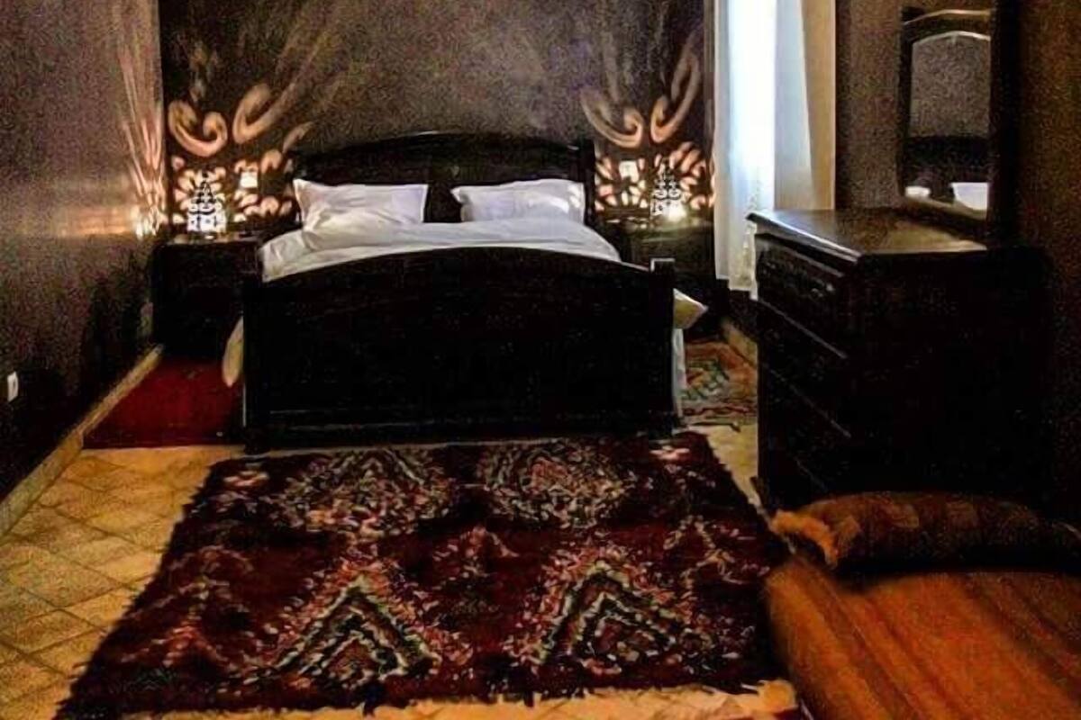 A bedroom with a bed, a nightstand, a dresser, and a television.