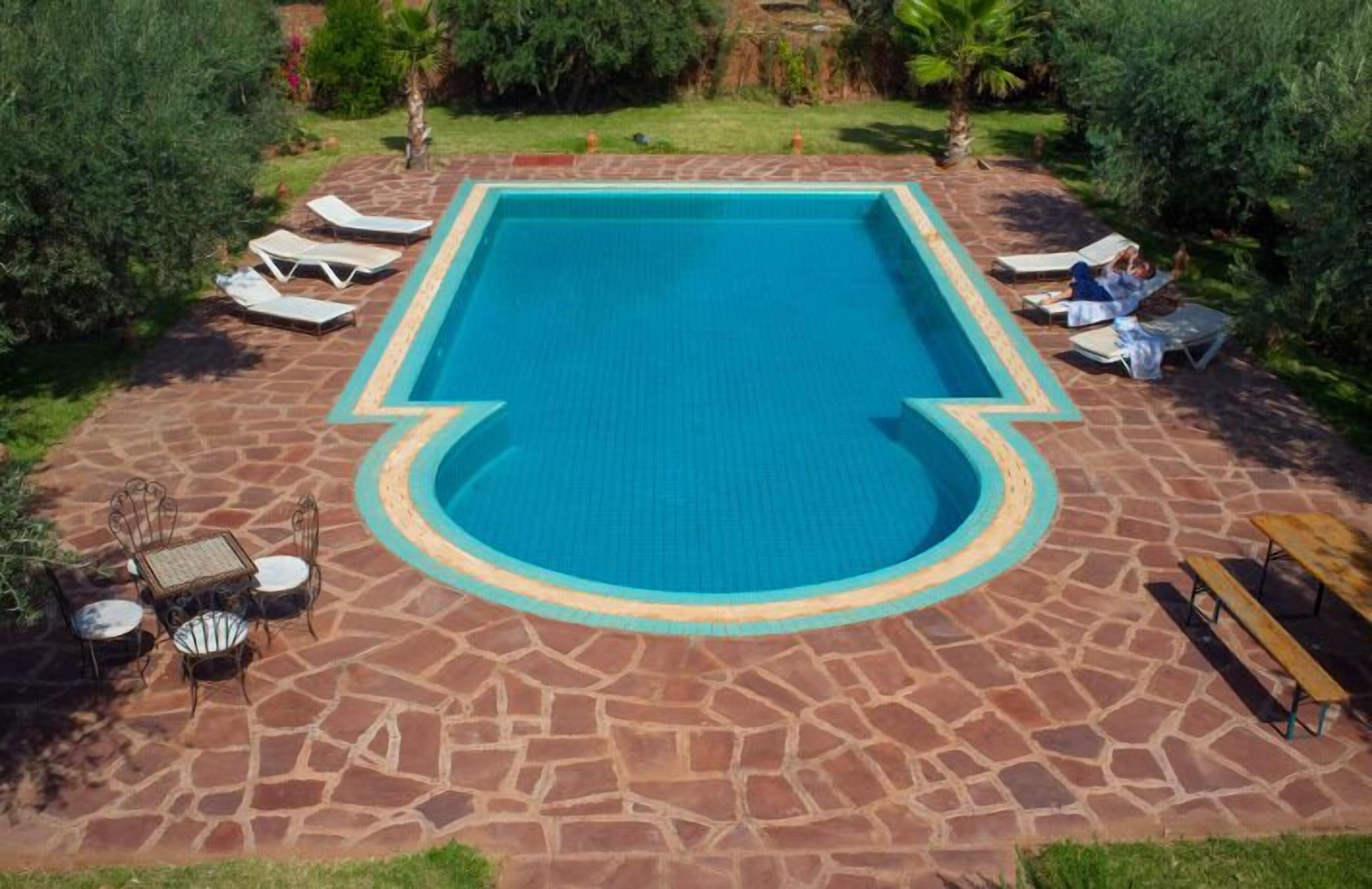 Una piscina al aire libre, sombrillas, sillones reclinables de piscina