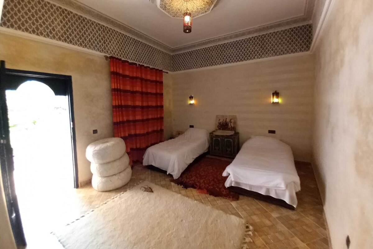 Quarto com duas camas, teto estampado e cortina vermelha.