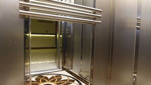 Interior de un ascensor con paredes metálicas y piso estampado.