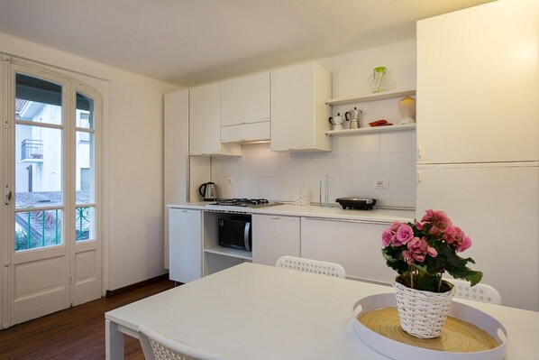 Una cocina moderna con armarios blancos, una mesa de comedor y una planta en maceta.