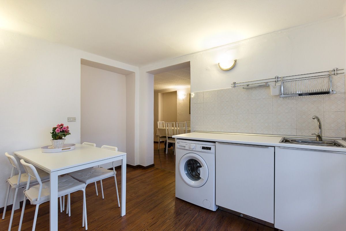 Une cuisine compacte comprenant un lave-linge, une table à manger avec des chaises et un petit coin salon.
