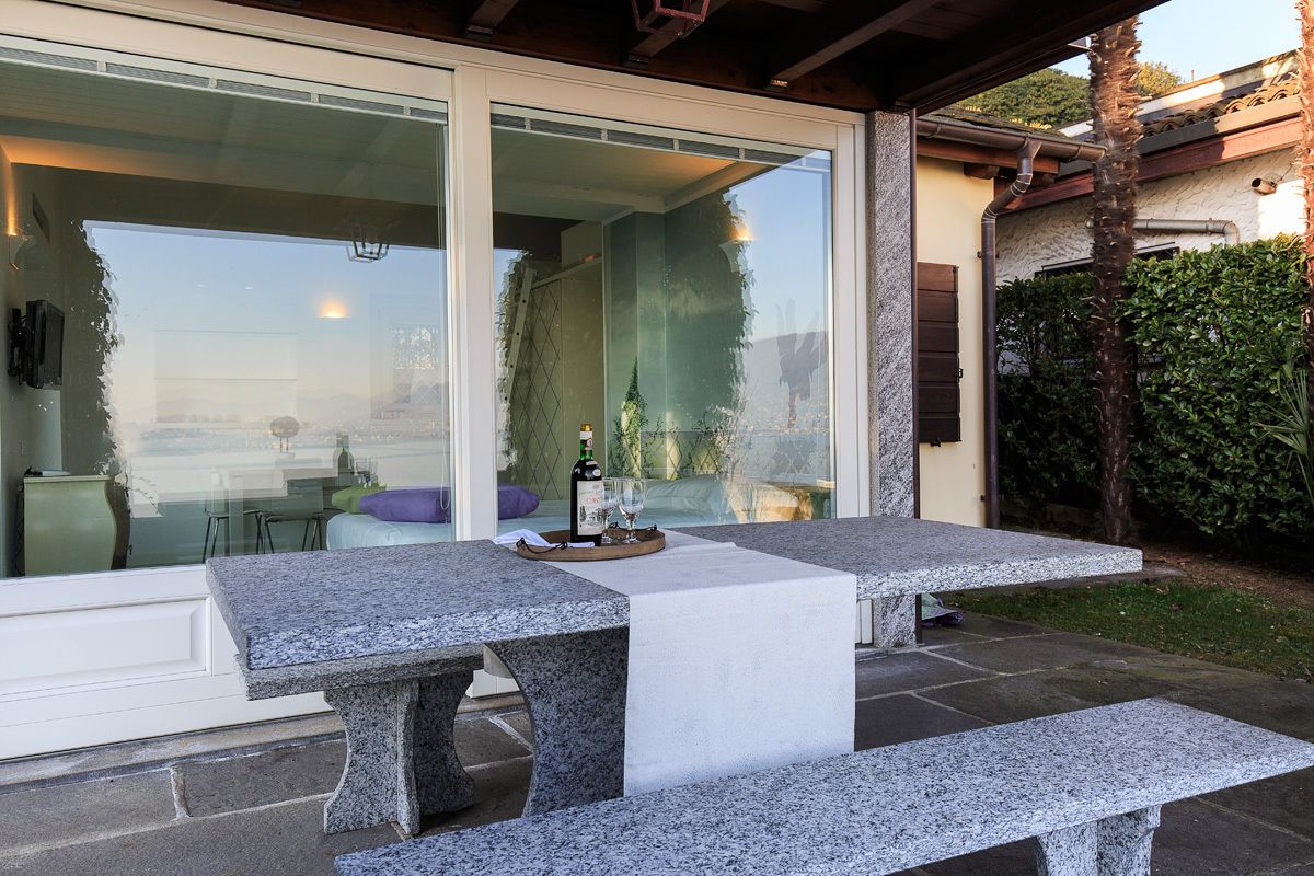 A patio with two granite tables, a bottle of wine, and glasses on a tray.