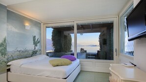 A bedroom with a bed, a TV, and a view of a body of water. - Impero House Rent - Maison du Lac (Baveno)