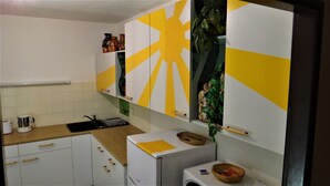 A kitchen with white cabinets, a sink, a coffee maker, and a washing machine. - Prázdninový dům Pacl (Cervená Recice)