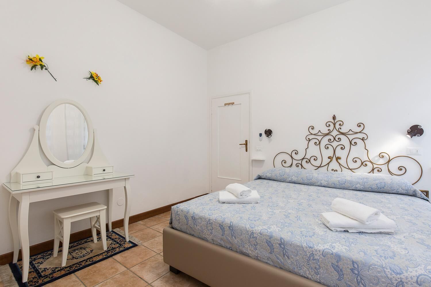 Une chambre à coucher avec un lit, une commode avec un miroir et une porte.