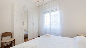 A bedroom with a large bed, a wooden chair, a wardrobe, and a chandelier. - Impero House Rent - Rampolina View (Stresa)