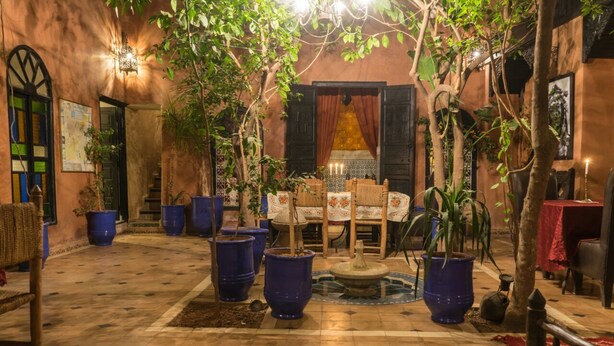 A cozy courtyard with a fountain, potted plants, and a dining area with a table and chairs. - Riad Sidi Omar (Marrakech)