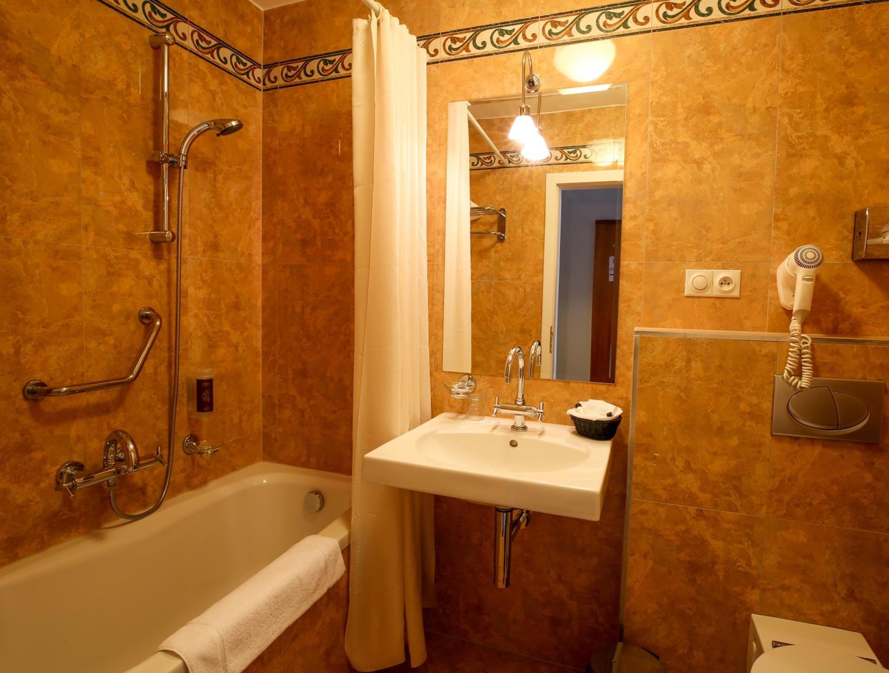 A bathroom with a bathtub, a sink, a mirror, a shower, and a hairdryer.