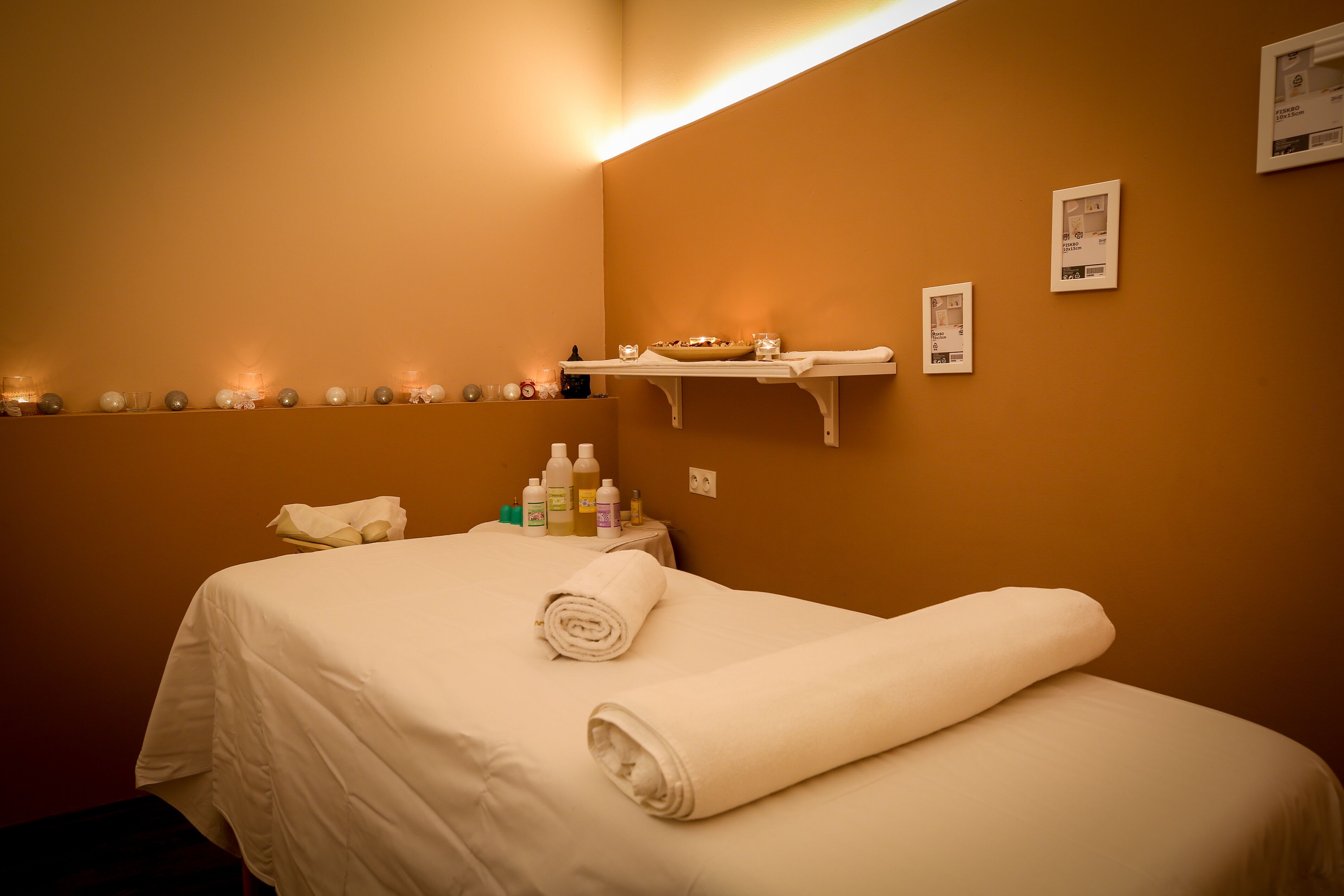 Ett hotellrum med en säng, en hylla med ljus och hygienartiklar.