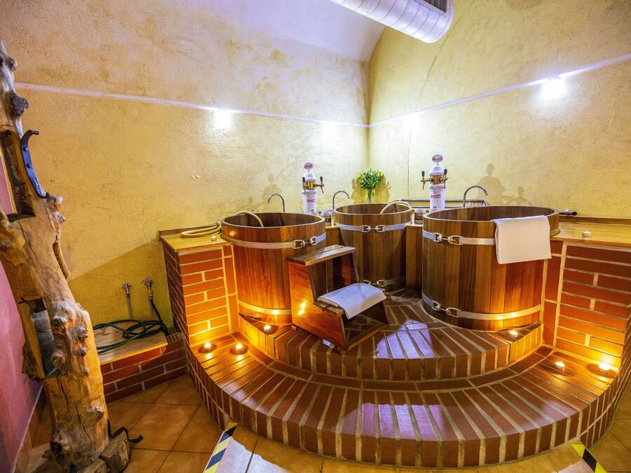 A spa area with wooden tubs, a brick bench, and a mirror.