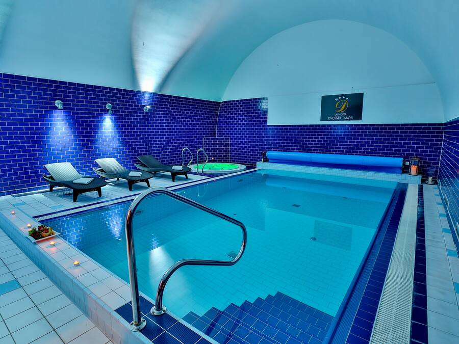 Una piscina con paredes de azulejos azules, sillas de descanso y un cartel que indica un hotel.