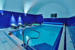 Una piscina con paredes de azulejos azules, sillas de descanso y un cartel que indica un hotel.