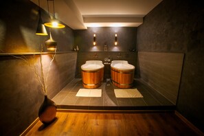 Een moderne badkamer met twee houten wasbakken, een houten vloer, en een vaas met takken.