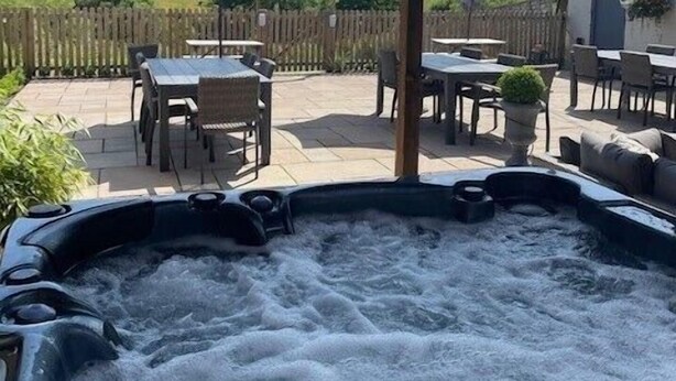 A hot tub under a wooden pergola with a view of a grassy landscape. - The Grousemoor Country House (Wrexham)