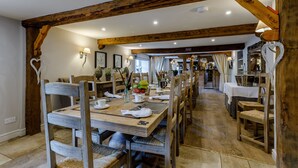 A dining area with wooden furniture, a long table set for multiple people, and a rustic ceiling. - The Grousemoor Country House (Wrexham)