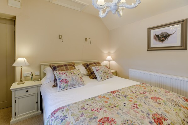 A bedroom with a bed, nightstands, lamps, a floral bedspread, a framed picture on the wall, and a chandelier. - The Grousemoor Country House (Wrexham)