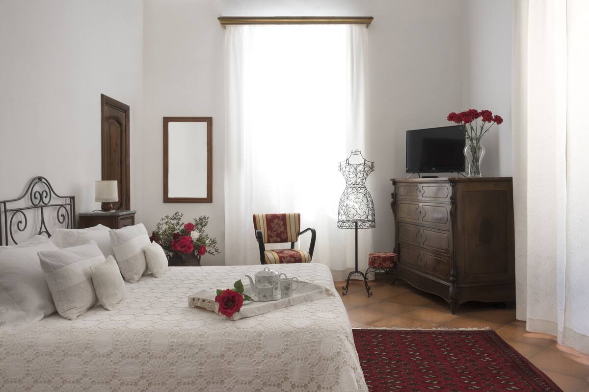 Une chambre à coucher comprenant un lit, une commode, un téléviseur et des objets de décoration.